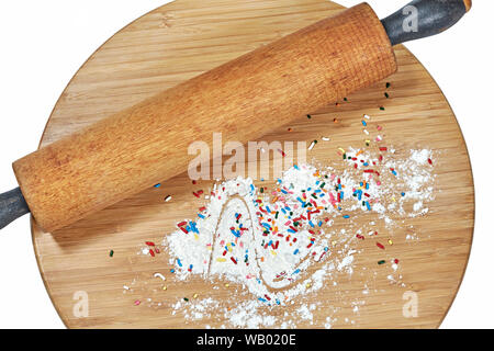 Un rouleau à pâtisserie en bois sur une planche à découper en bambou avec de la farine blanche et multicolore arrose au conseil isolated on white Banque D'Images