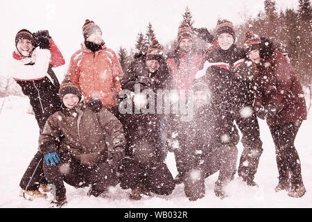 Groupe de jeunes happy business people having fun throwing snow dans l'air tout en profitant de l'hiver neigeux journée avec flocons autour d'eux pendant une équipe bui Banque D'Images