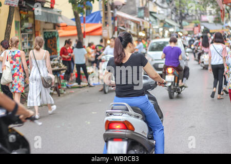 Une femme est à cheval sur une moto à Hanoi, Vietnam. Banque D'Images