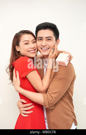 Jeune couple hugging avec wrapped present. woman embracing man et holding present avec ruban Banque D'Images