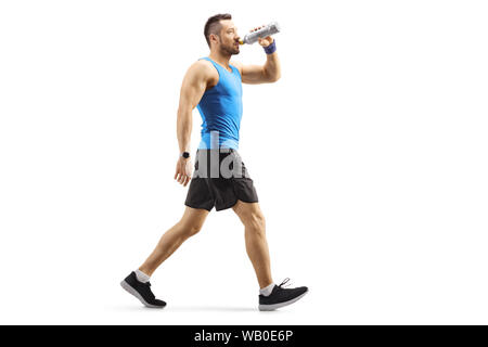 Profil complet tiré d'un bon jeune homme dans les vêtements de sport et de marche de boire une boisson énergétique sports isolé sur fond blanc Banque D'Images