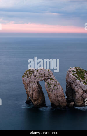 Urros Manzano étranges dans des vagues furieuses à nuageux coucher du soleil à la côte de la Cantabrie, dans le Nord de l'Espagne Banque D'Images