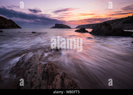 Lever du soleil coloré sur la plage de Playa de la arnia dynamique avec les vagues et les rochers bizarres, Liencres, le nord de l'Espagne Banque D'Images