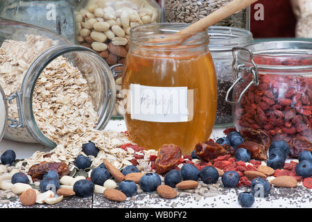 Pot de miel avec des baies, noix et graines d'avoine Banque D'Images