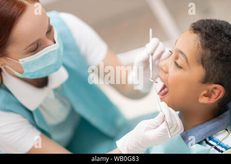 Red-haired child wearing mask dentiste examinant cute boy Banque D'Images