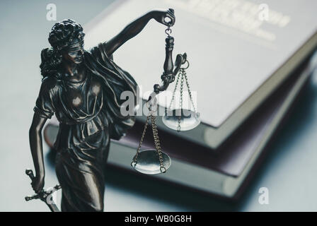 Statue de la figure de la Justice tenant une épée et des balances high angle contre livres de droit en cour symbolique de la loi Banque D'Images