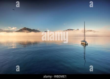 Und Niesen Stockhorn dominant un banc de brouillard du matin au lac de Thoune avec un bateau à voile sur une bouée d'ancre la réflexion sur la surface de l'eau Banque D'Images