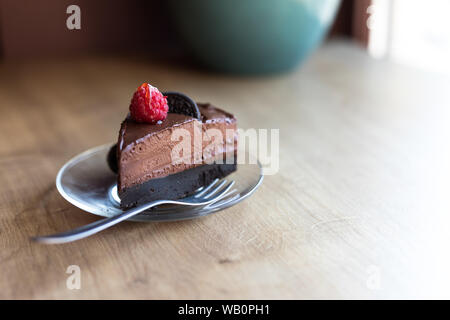 Un morceau de gâteau au chocolat avocat végétalien avec le biscuit oreo et la framboise vive sur le dessus. Désert de végétalien. Banque D'Images