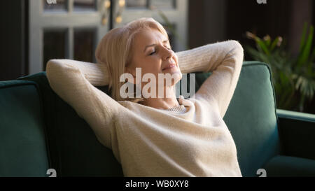 Vieille Femme heureux calme reposant, avec les yeux fermés sur la table Banque D'Images