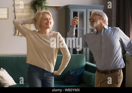 Heureux retraité actif elder couple dansant ensemble dans la salle de séjour Banque D'Images