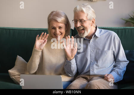 Happy senior couple faisant des signes avec la main de chat vidéo en ligne Banque D'Images