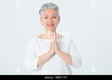 Happy mature femme croisa ses mains en Asie de vœux. Les femmes d'âge moyen à joindre les mains à méditer. Concept - calme, spirituel, de croyance, de la paix. Banque D'Images