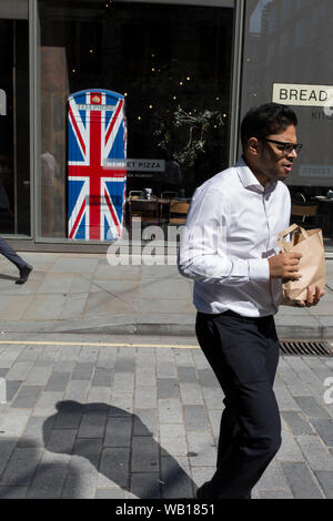 Les travailleurs de la ville de midi passé l'Union Jack-thèmes téléphone kiosque dans le célèbre chef Gordon Ramsay's restaurant Bread Street Kitchen (sur l'ancienne voie romaine) Watling Street, dans la ville de Londres, le quartier financier de la capitale (aka le Square Mile), le 22 août 2019, à Londres, en Angleterre. Banque D'Images