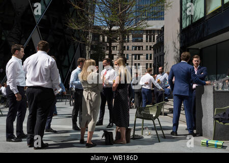 Les travailleurs de la ville de midi prendre un verre au soleil d'été à l'extérieur du bâtiment de Swiss Re (aka le Gherkin), dans la ville de Londres, le quartier financier de la capitale (aka le Square Mile), le 22 août 2019, à Londres, en Angleterre. Banque D'Images