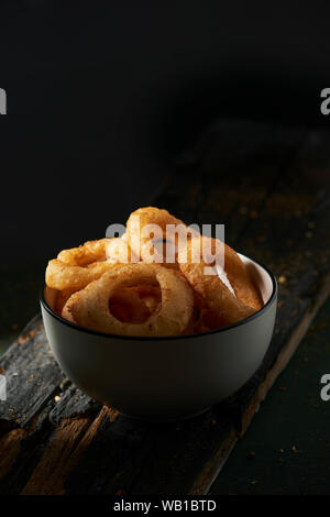 Libre d'un bol en céramique blanc avec quelques calamares a la romana, Fried squid battues typique de l'Espagne, les anneaux sur une table rustique en bois foncé contre un Banque D'Images