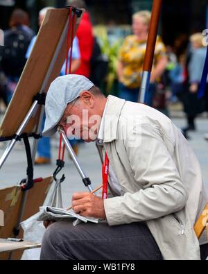 Edinburgh, Royaume-Uni. Août 22, 2019. Les artistes et les interprètes autour de la butte sur Princess Street Édimbourg. Un artiste prend le temps de faire les mots croisés. Crédit : Chris McNulty/Alamy Live News Crédit : Chris McNulty/Alamy Live News Banque D'Images