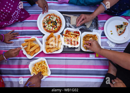 Watford, Royaume-Uni. 23 août 2019. Une famille jouit d'aliments traditionnels comme des milliers de célébrer la naissance du Seigneur Krishna Janmashtami au festival au Bhaktivedanta Manor temple Hare Krishna à Watford, Hertfordshire. Le manoir a été donné à la mouvement Hare Krishna par ex Beatle George Harrison et accueille chaque année le plus grand festival de Janmashtami en dehors de l'Inde. Crédit : Stephen Chung / Alamy Live News Banque D'Images