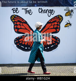 Watford, Royaume-Uni. 23 août 2019. Un dévot promenades par un mur graphique afficher comme des milliers de célébrer la naissance du Seigneur Krishna Janmashtami au festival au Bhaktivedanta Manor temple Hare Krishna à Watford, Hertfordshire. Le manoir a été donné à la mouvement Hare Krishna par ex Beatle George Harrison et accueille chaque année le plus grand festival de Janmashtami en dehors de l'Inde. Crédit : Stephen Chung / Alamy Live News Banque D'Images