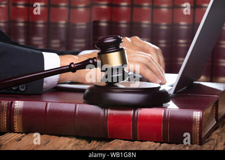 Homme juge dans une salle d'audience de la saisie sur ordinateur portable en face de Gavel Banque D'Images