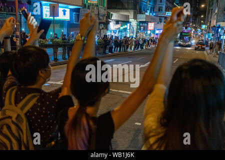 Hong Kong les protestataires d'âges différents tenir la main de l'autre côté de la route, dans un quartier résidentiel local occupé à former une chaîne humaine pour appeler à la démocratie. Ils s'installèrent alors retour à la chaussée lorsque le feu de circulation pour les piétons devient rouge pour laisser passer les véhicules la.Des milliers de manifestants à Hong Kong mains lien pour former une chaîne humaine à travers la ville pour appeler à la démocratie. Les chaînes, qui remonte trois itinéraires de métro, totalisant environ 40 kilomètres (25 milles) de longueur. Les manifestants ont déclaré qu'ils ont été inspirés par la "Voie balte", quand des millions créé une chaîne à travers trois pays (Estonie, Lettonie et Lithua Banque D'Images