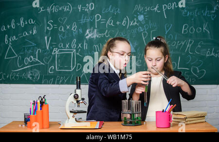 Faire en chimie intéressant. Expérience Pédagogique concept. Microscope et de tubes à essai sur table. Attention l'exécution de la réaction chimique. Connaissances de base en chimie. Les filles étudient la chimie. Banque D'Images