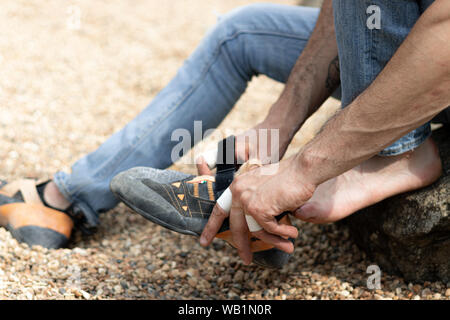 Boy putting sur ses chaussures d'escalade dans un espace extérieur Banque D'Images