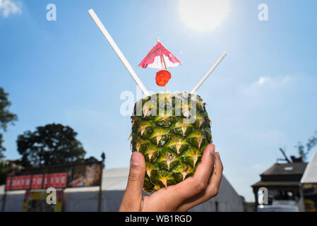 Watford, Royaume-Uni. 23 août 2019. Un dévot est titulaire d'un un verre d'ananas rafraîchissante pour célébrer la naissance du Seigneur Krishna Janmashtami au festival au Bhaktivedanta Manor temple Hare Krishna à Watford, Hertfordshire. Le manoir a été donné à la mouvement Hare Krishna par ex Beatle George Harrison et accueille chaque année le plus grand festival de Janmashtami en dehors de l'Inde. Crédit : Stephen Chung / Alamy Live News Banque D'Images