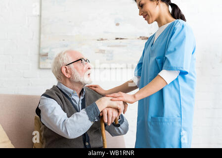 Vue latérale d'un homme âgé et nurse standing en chambre, à l'un l'autre Banque D'Images