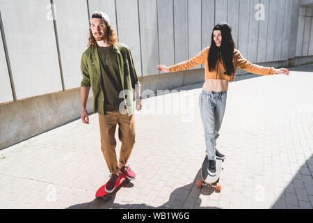 Portrait de l'homme et de la femme tendre la main à cheval sur planche près de mur de béton Banque D'Images