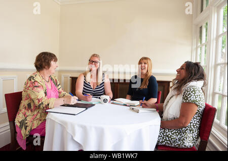 Les femmes habillées de façon informelle en discussion assis autour d'une table Banque D'Images