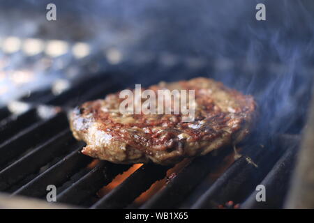 Des hamburgers. Flamme de hamburgers grillés sur le barbecue au gaz Banque D'Images