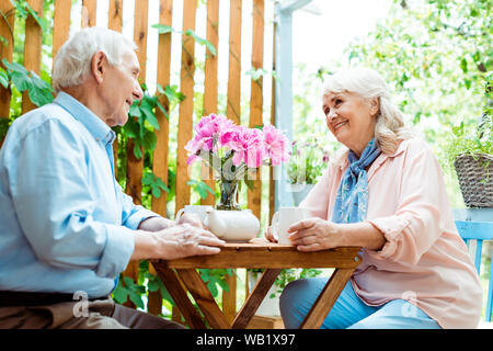 Low angle view of happy senior man smiling femme près de fleurs roses Banque D'Images