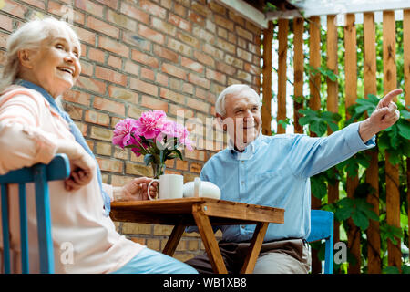 Low angle view of happy senior homme pointant avec le doigt près de femme joyeuse Banque D'Images