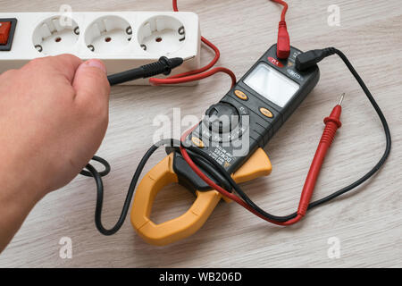 électricien utilisant un compteur numérique pour mesurer la tension à une  prise murale sur un mur en bois. 3478568 Photo de stock chez Vecteezy