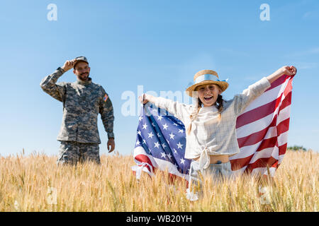 Focus sélectif de l'heureux enfant debout avec le drapeau américain près de soldat Banque D'Images