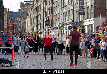 Royal Mile, Edinburgh, Ecosse, Royaume-Uni. 23 août 2019. Jongleur sur le Lawnmarket taquine un jeune volontaire qui tente d'attraper l'une des balles de jonglage. Banque D'Images