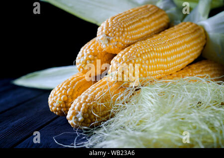 Maïs bonduel jaune juteux frais avec des feuilles vertes se trouve sur la table en bois Banque D'Images