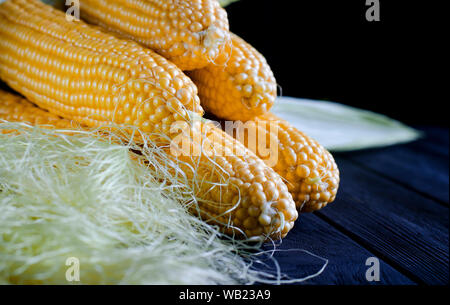 Maïs bonduel jaune juteux frais avec des feuilles vertes se trouve sur la table en bois Banque D'Images