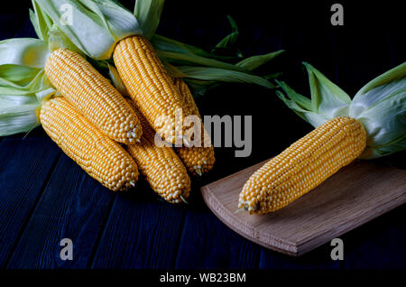 Maïs bonduel jaune juteux frais avec des feuilles vertes se trouve sur la table en bois Banque D'Images