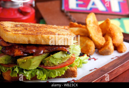 Sandwich au poulet barbecue avec de l'avocat et la laitue avec pommes de terre rôties fils le côté Banque D'Images