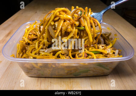 Chinois à emporter / soft à emporter (nouilles chow mein de viande et de légumes) dans un contenant de plastique, et certains sont sortis pour manger avec une fourchette. Banque D'Images