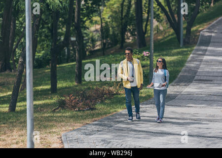 Happy mixed race man et attractive woman walking in park Banque D'Images