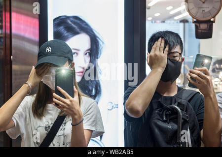 Les protestataires couvrir leur œil droit en face d'une actrice chinoise Liu Yifei annonce commerciale au cours de la Hong Kong façon rallye anti-gouvernement à Kowloon à Hong Kong. Les manifestations de masse continuent encore un week-end à Hong Kong qui a commencé en juin 2019 sur un projet de loi sur l'extradition suspendue-maintenant à la Chine. Banque D'Images