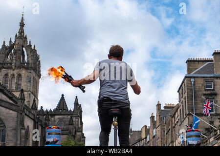 Edinburgh, Ecosse, Royaume-Uni. 23 août, 2019. Un artiste de rue sur le Royal Mile assis sur un monocycle géant et tenant des torches enflammées au cours de l'Edinburgh Fringe Festival. Credit : Skully/Alamy Live News Banque D'Images