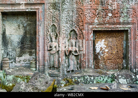 Bas-relief en grès sculpté Apsaras (maidens céleste) et fenêtre en pierre de bars à Ta Prohm temple à Siem Reap, Cambodge. Banque D'Images