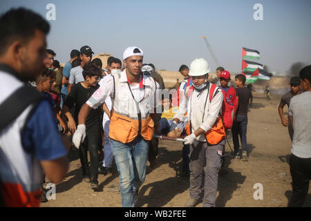 Gaza, la Palestine. Août 23, 2019. Les médecins palestiniens portent un garçon blessé lors d'affrontements avec les troupes israéliennes sur la frontière Gaza-Israel, à l'est du sud de la bande de Gaza ville de Khan Younis, le 23 août 2019. Au moins 122 Palestiniens, y compris trois ambulanciers, ont été blessés vendredi lors d'affrontements avec des soldats israéliens à l'est de Gaza. Credit : Khaled Omar/crédit : Xinhua Xinhua/Alamy Live News Banque D'Images