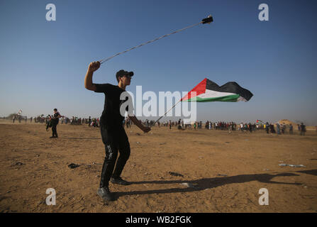 Gaza, la Palestine. Août 23, 2019. Un manifestant palestinien utilise une fronde pour lancer des pierres sur des soldats israéliens lors d'affrontements sur la frontière Gaza-Israel, à l'est du sud de la bande de Gaza ville de Khan Younis, le 23 août 2019. Au moins 122 Palestiniens, y compris trois ambulanciers, ont été blessés vendredi lors d'affrontements avec des soldats israéliens à l'est de Gaza. Credit : Khaled Omar/crédit : Xinhua Xinhua/Alamy Live News Banque D'Images