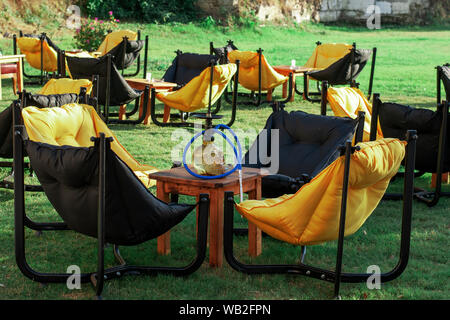 Sacs et fauteuils tables sur l'herbe dans un café. Le narguilé sur la table. L'intérieur de l'été cafe. Meuble d'été dans un restaurant Banque D'Images