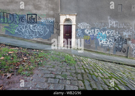 Une porte sur un mur couvert de graffitis sur une colline très raide à Bristol, Royaume Uni Banque D'Images