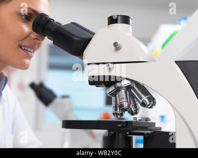 Examen médical. Scientist examining une lame de verre contenant un échantillon humain sous un microscope. Banque D'Images